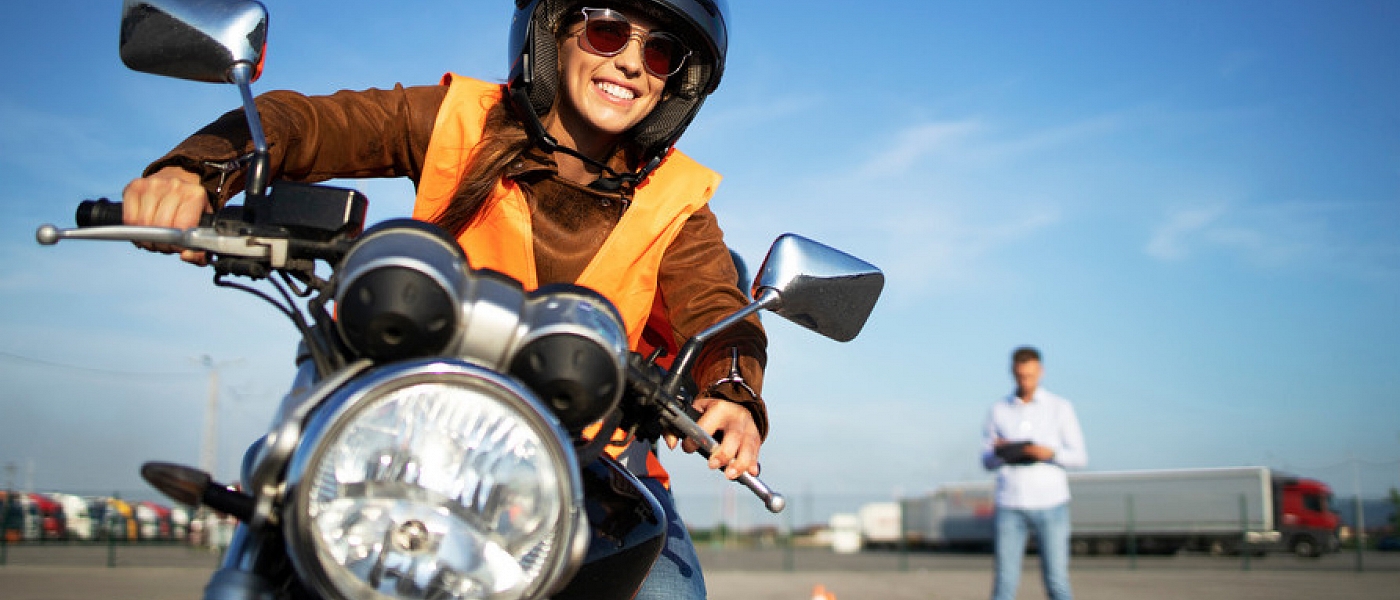 a woman driving through a road course with motorcycle with the instructor in the back
