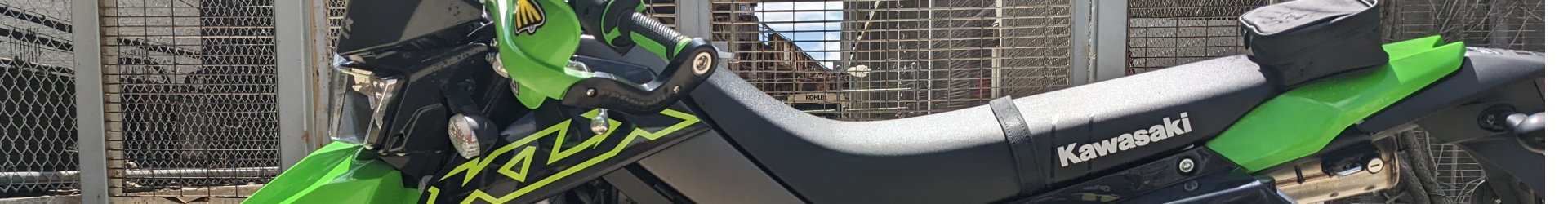 Side profile of green motorcycle posted outside in the sunlight