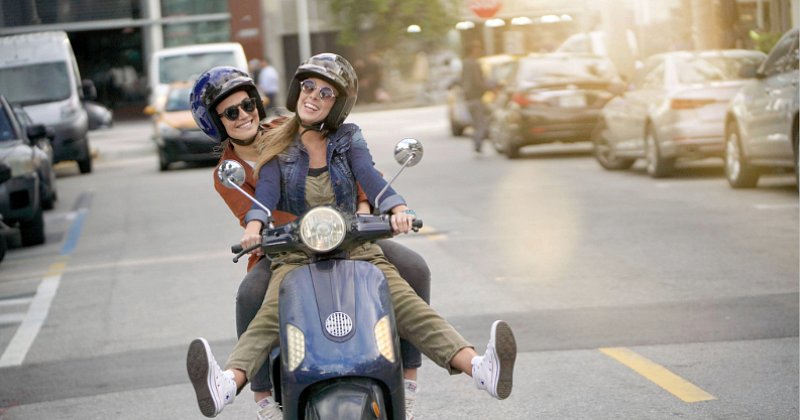 Woman in black gear riding green motorcycle