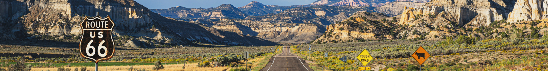 Sign of Route 66 with mountains in the background and a clear road leading to it
